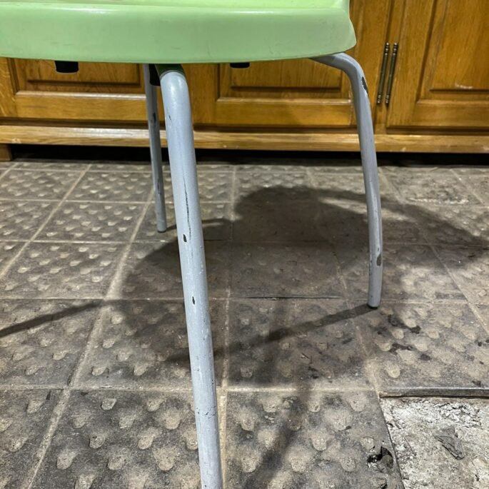 Zaļš plastmasas krēsls ar metāla kājām
